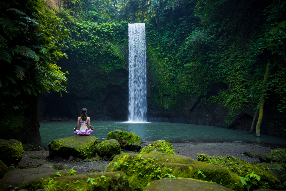 Young Caucasian woman sitting on the stone, meditating, practicing yoga