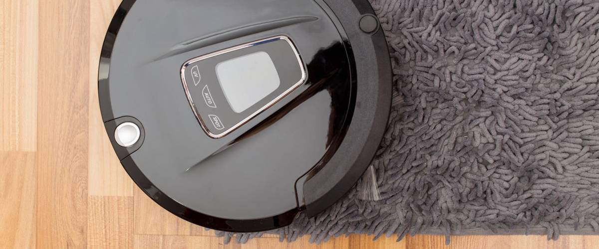 Robot vacuum cleaner on laminate wood floor, Smart robotic automate wireless cleaning technology machine in living room.